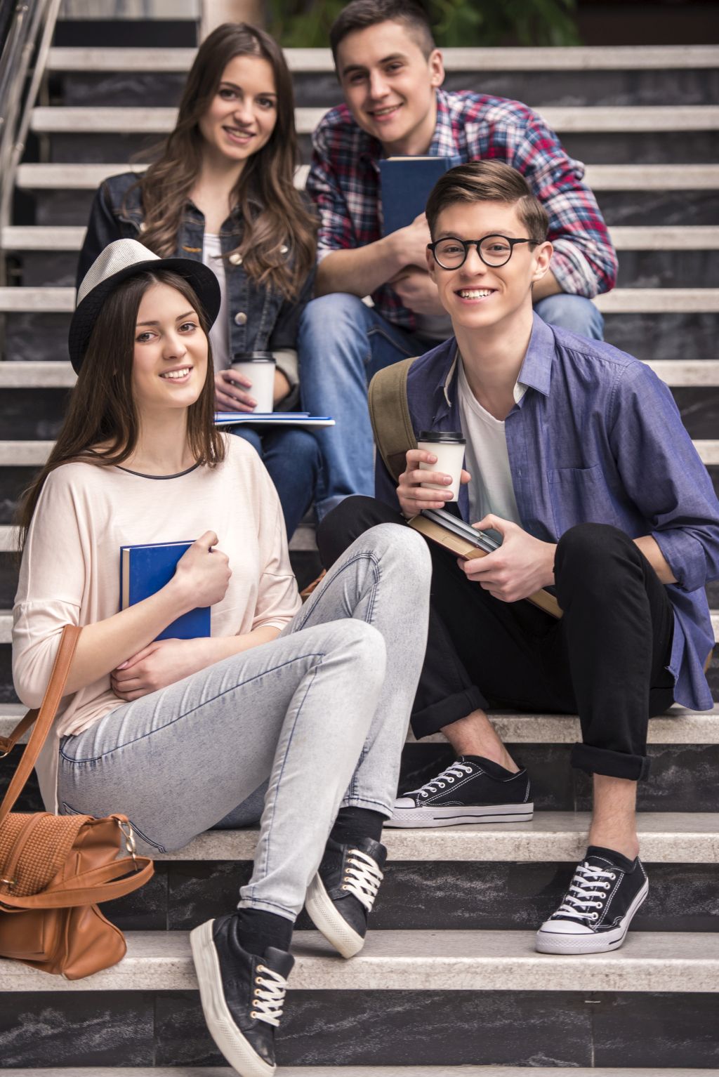 Three young students learning on stairs in college.